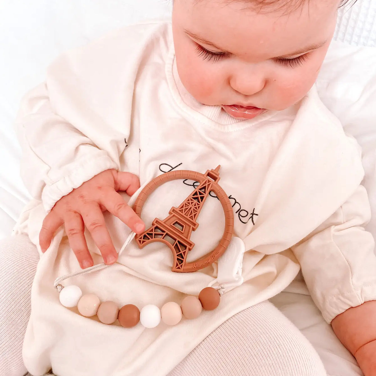 Baby playing with Paris silicone teething toy featuring an Eiffel Tower design and soft textured beads.