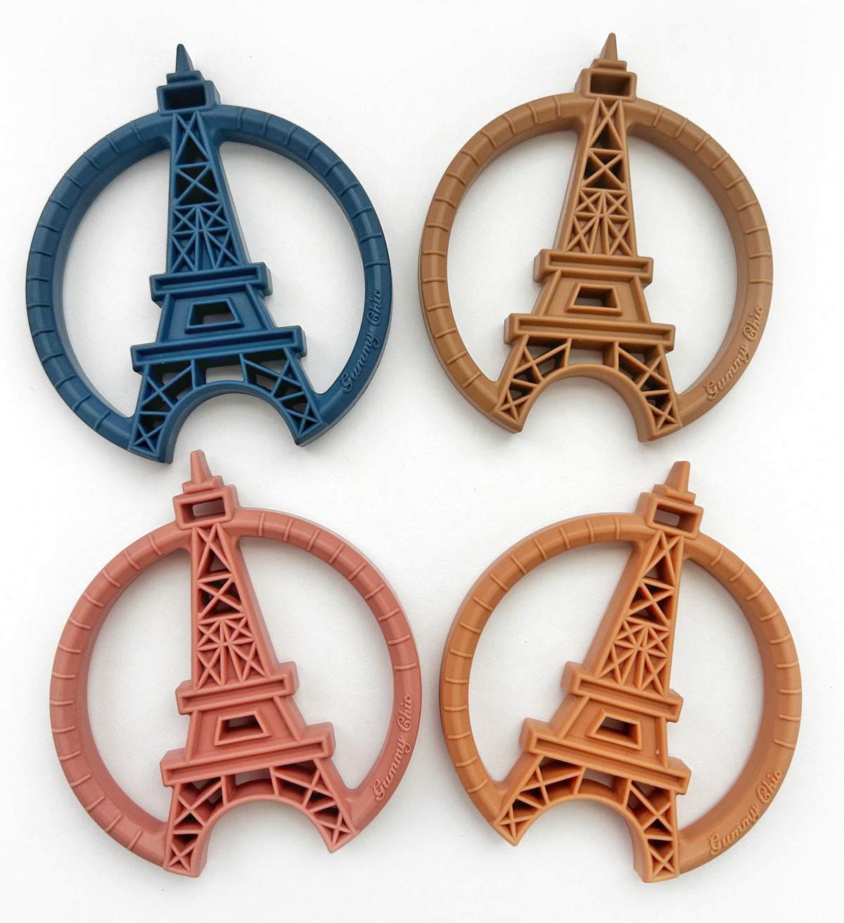 Paris silicone teething toy set featuring four colorful Eiffel Tower designs in blue, pink, and two earthy tones.