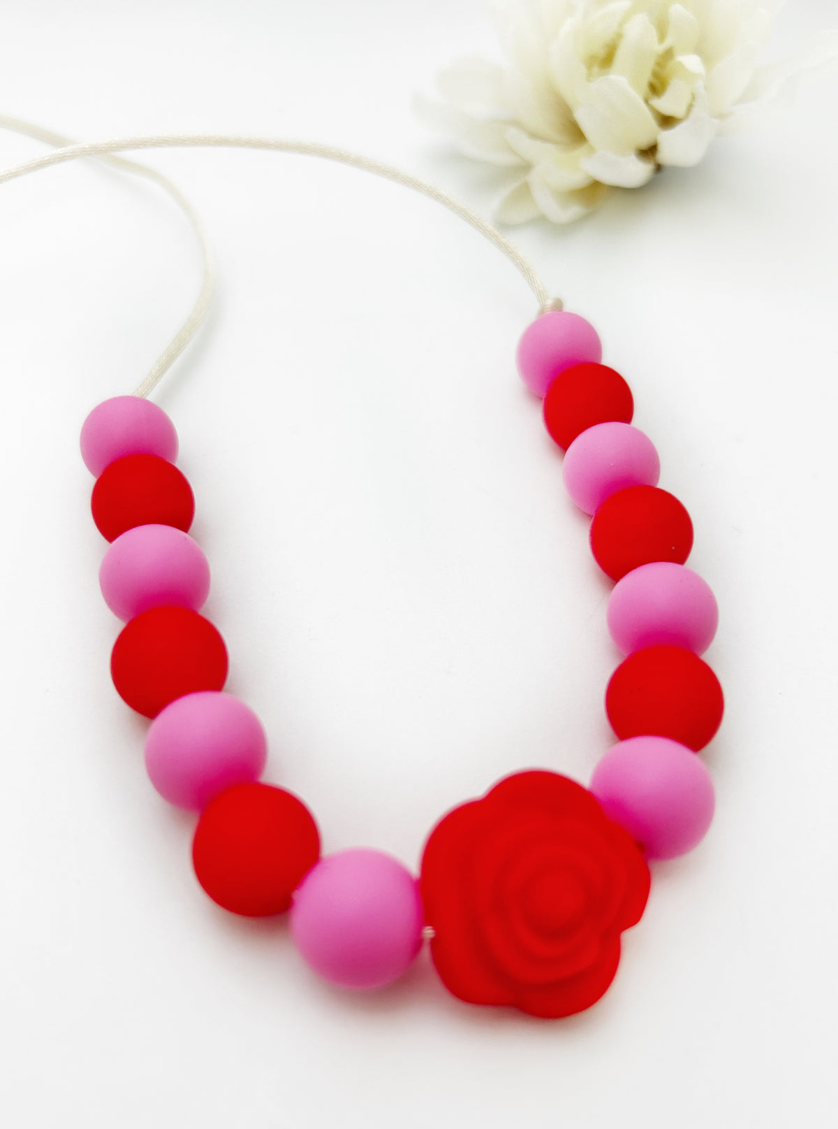 Necklace with pink and red beads and a red flower pendant on a white background