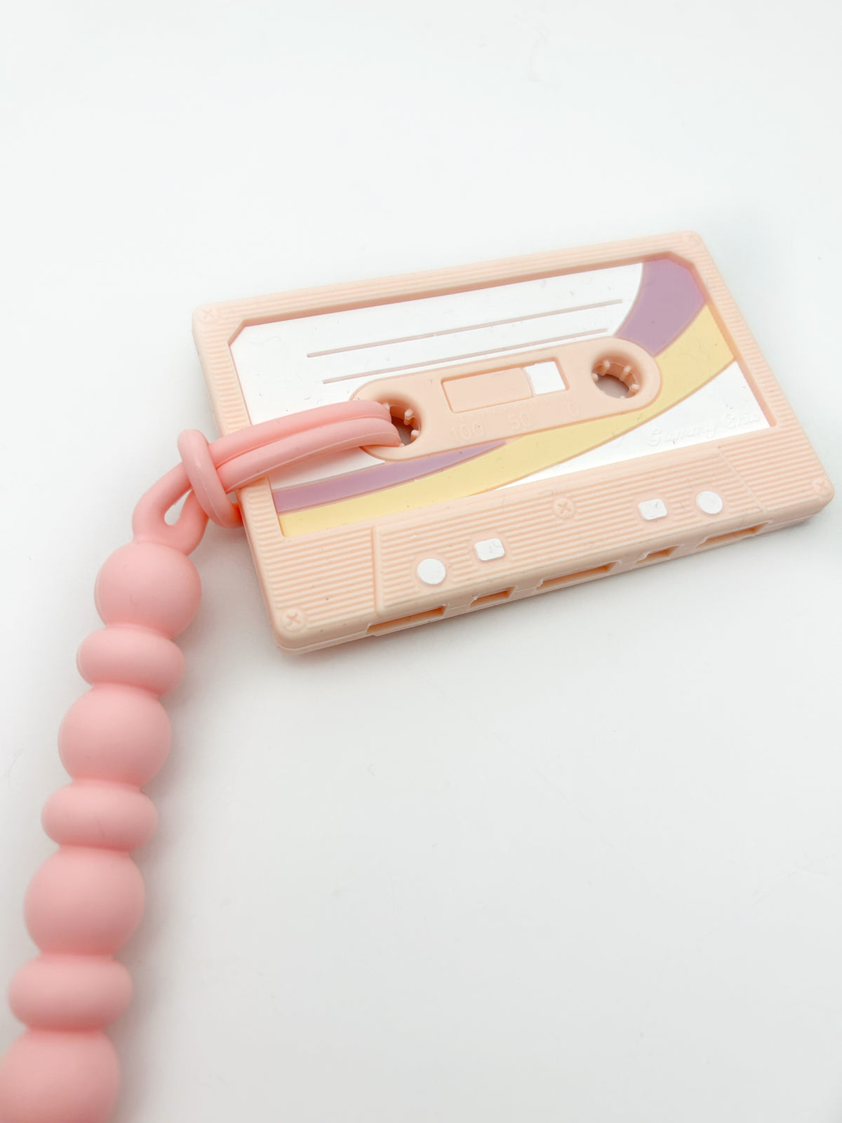 Cassette Mix Tape Teether in pink with retro design for teething relief, inspired by 80s and 90s nostalgia.