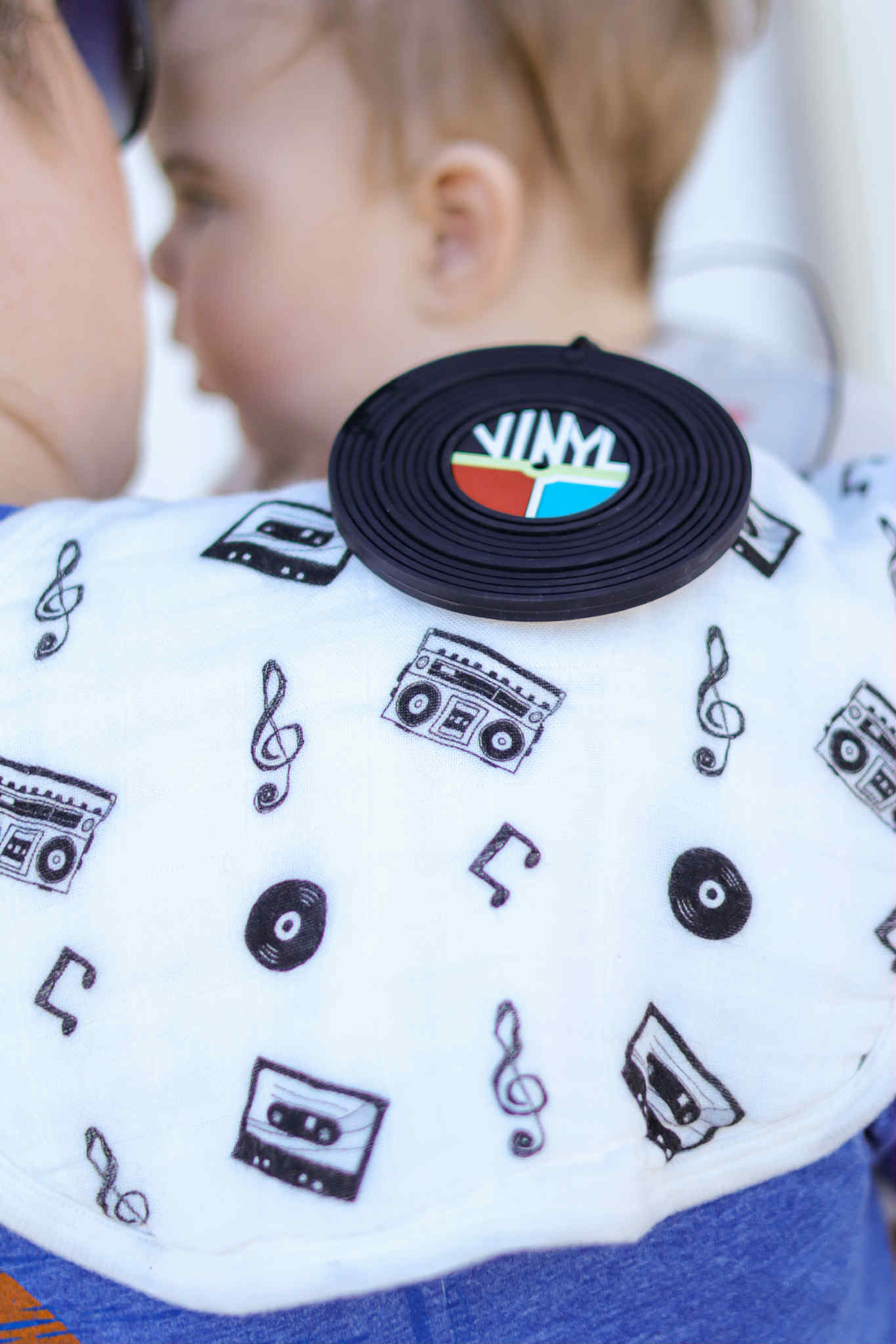Baby wearing a bib with music-themed designs and a 'Vim' logo.