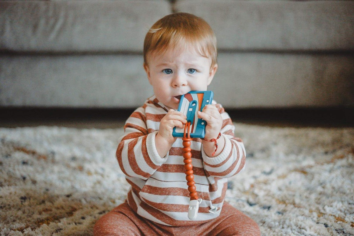 blue and orange silicone teething toy with baby chewing