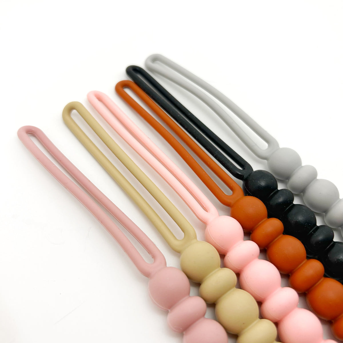 Set of colorful silicone pacifier clip loops on a white background
