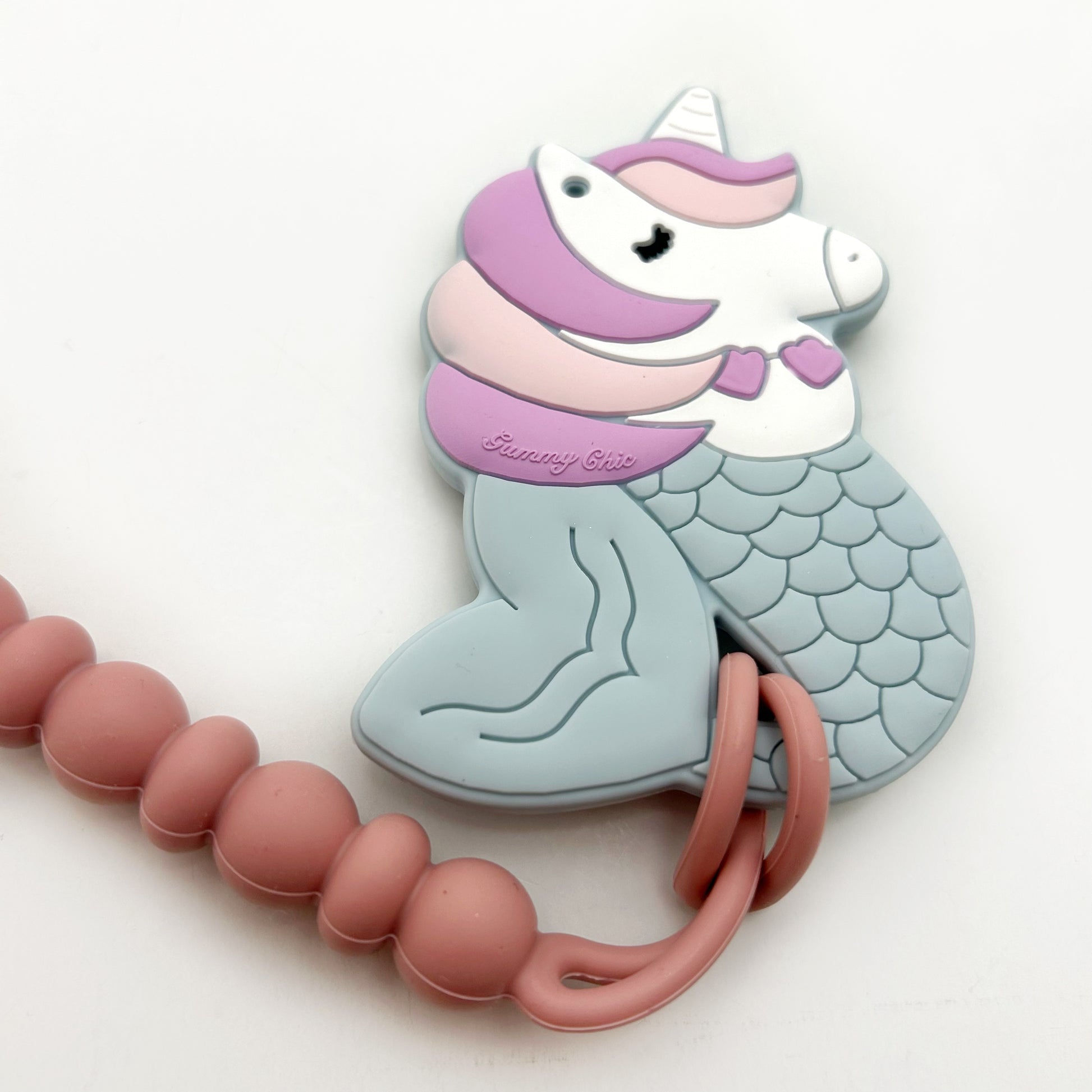 A clip-on teether featuring a whimsical mermaid and unicorn hybrid design, in pastel colors, with a clip attachment and silicone beads.
