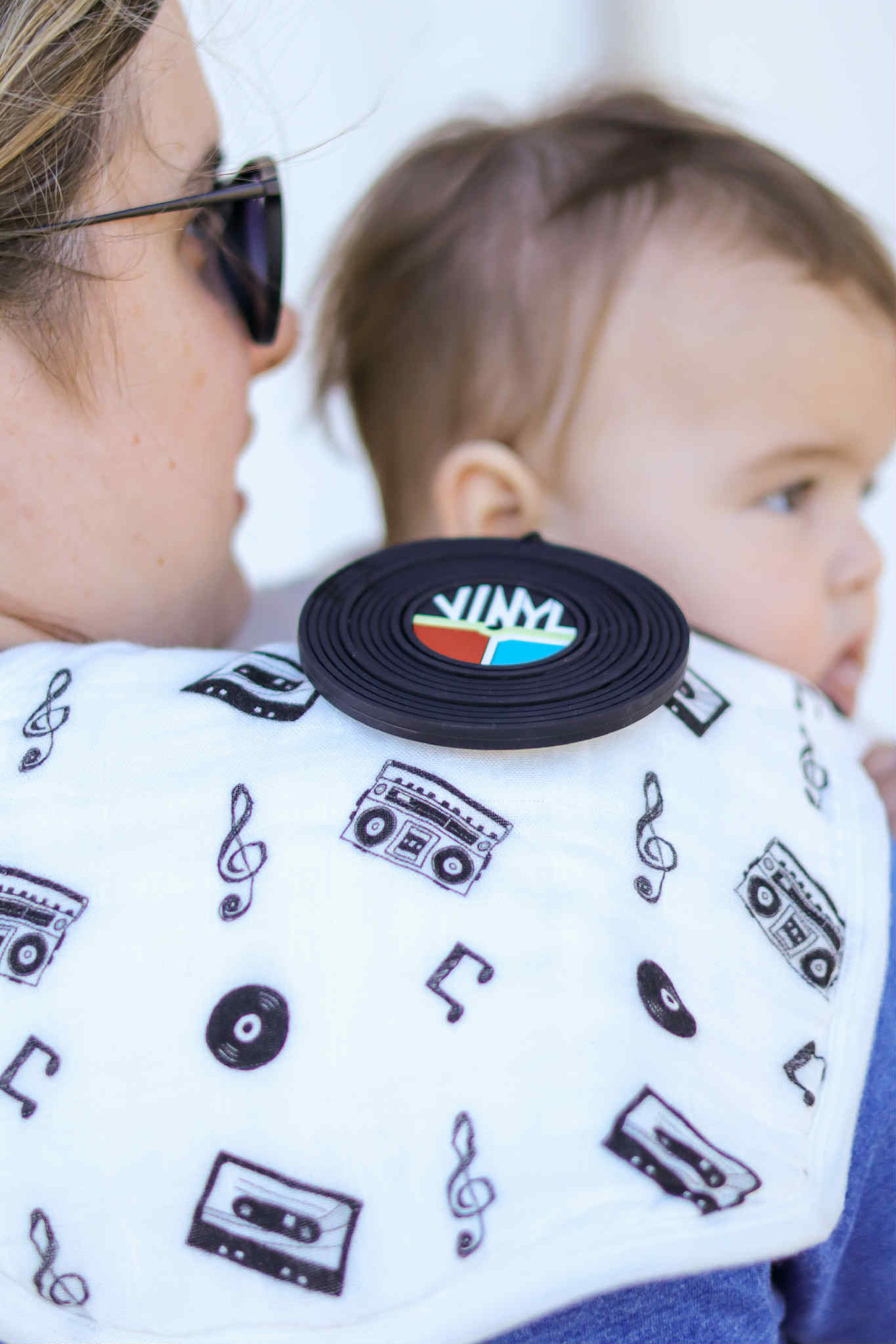 Baby wearing a bib with music-themed designs, held by a person.