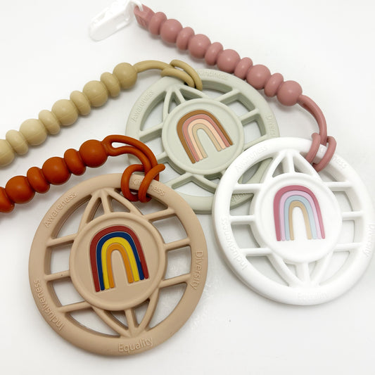 A multicolored baby teether with a rainbow design and silicone beads, featuring a plastic alligator clip and a gummy bead strap.