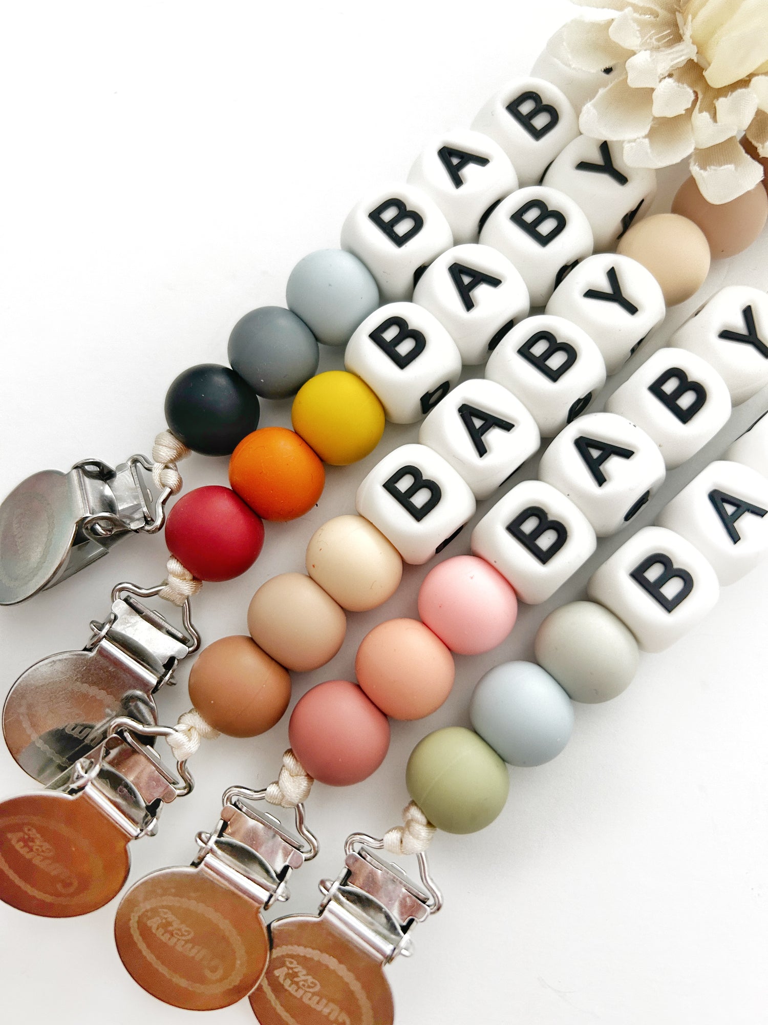 Add your name to these personalized pacifier clips with silicone beads in pastel colors, black and grey, orange and red and gender neutral beige with stainless steel