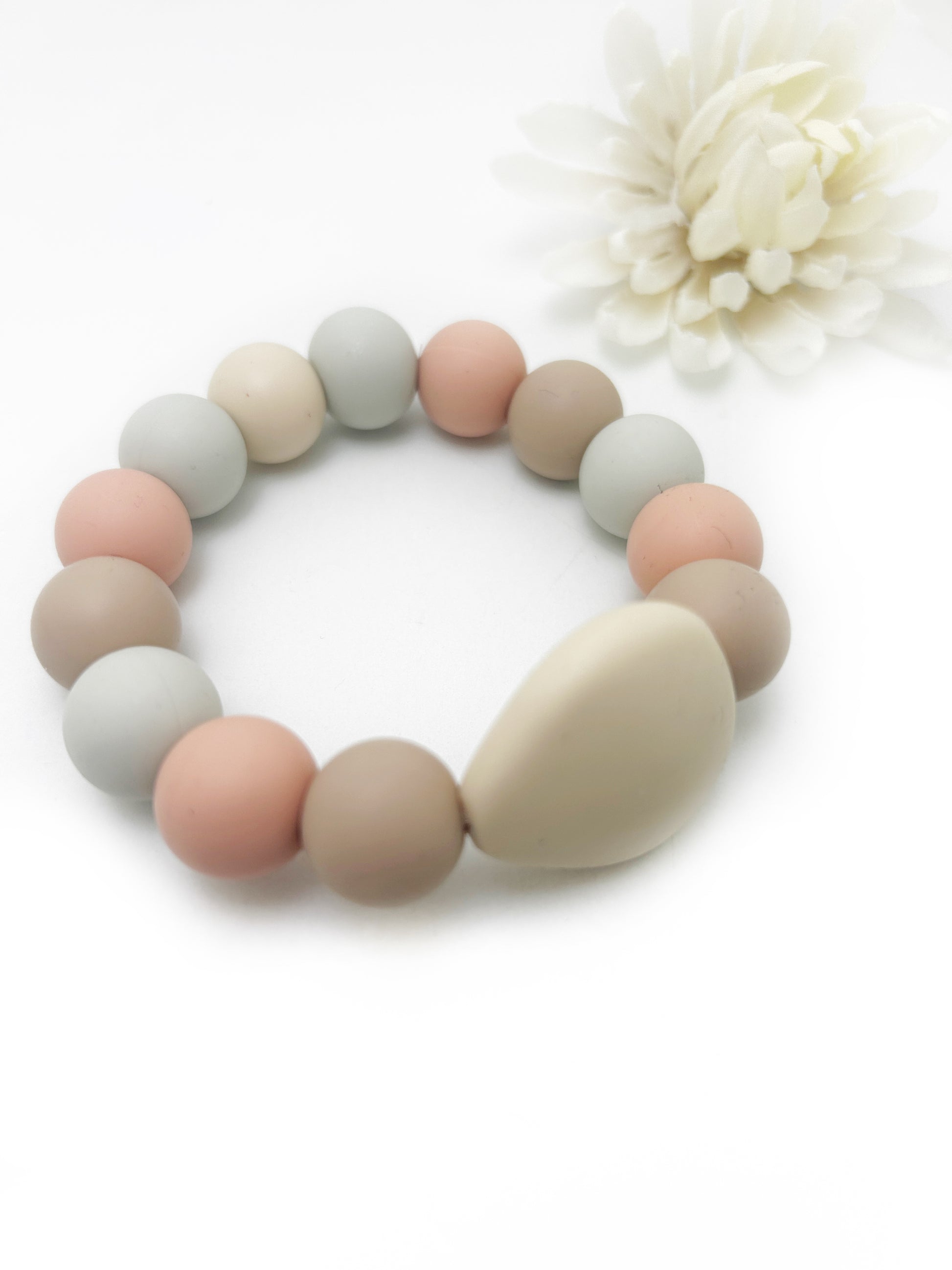 Multicolored beaded bracelet on a white background with a white flower.