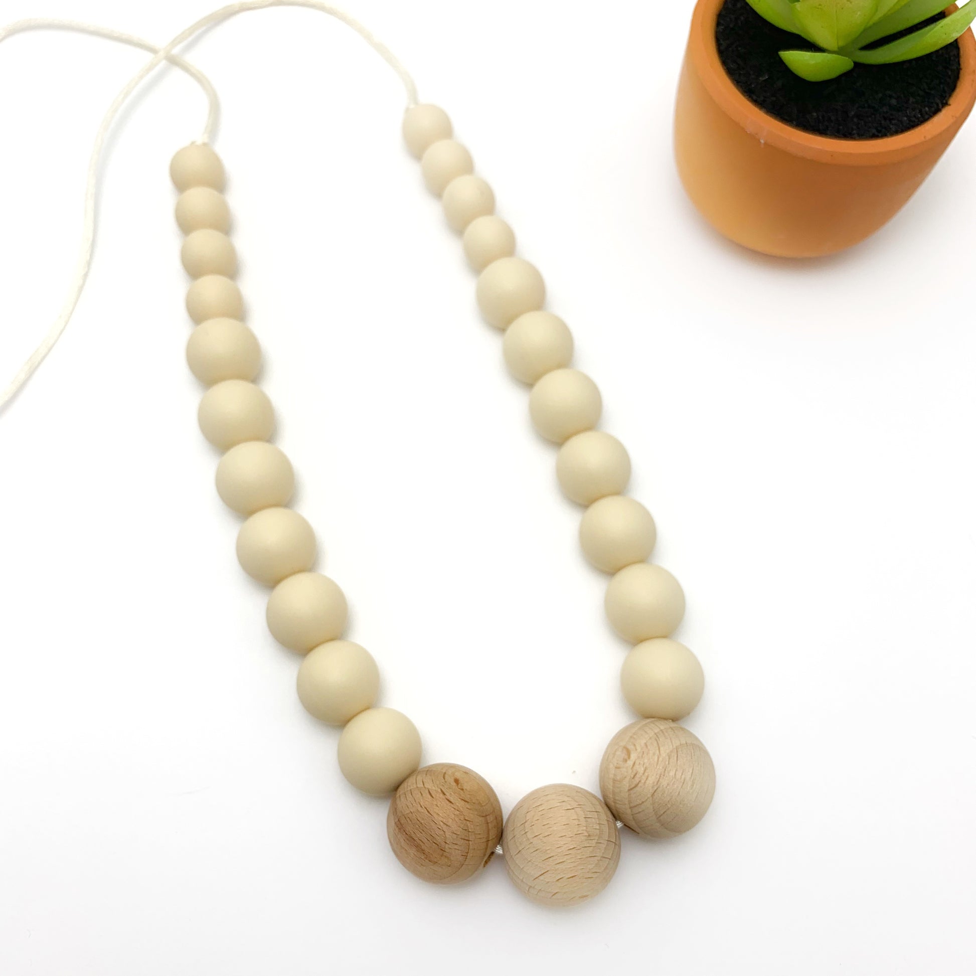 teething necklace in beige beads and wooden beads in the center for mom to wear