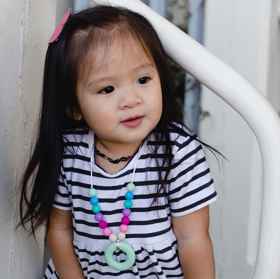 little girl modeling a mint pendant with rainbow beads necklace