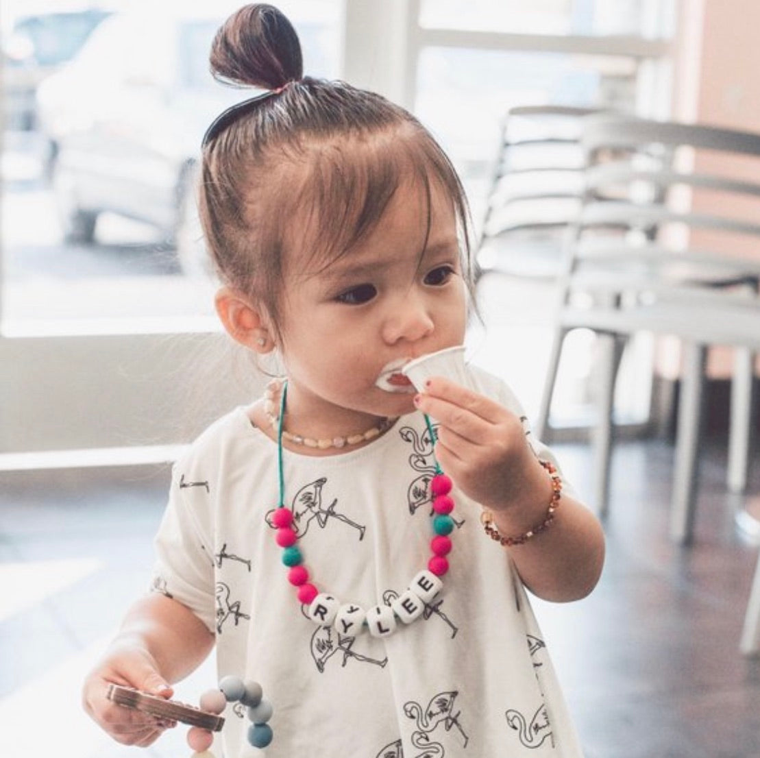 Girl wearing a personalized fidget chew necklace for kids, playing and chewing on a toy.