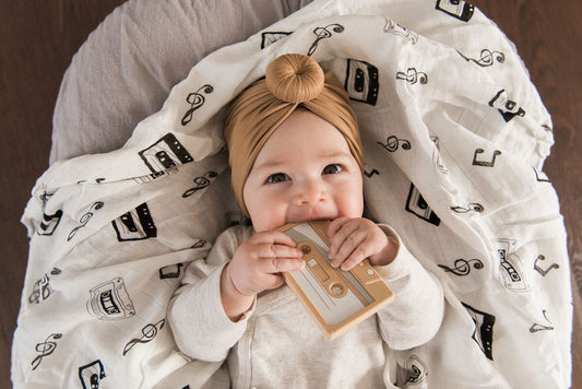 A baby lying on a swaddle blanket with a monochromatic black and white cassette tape design.