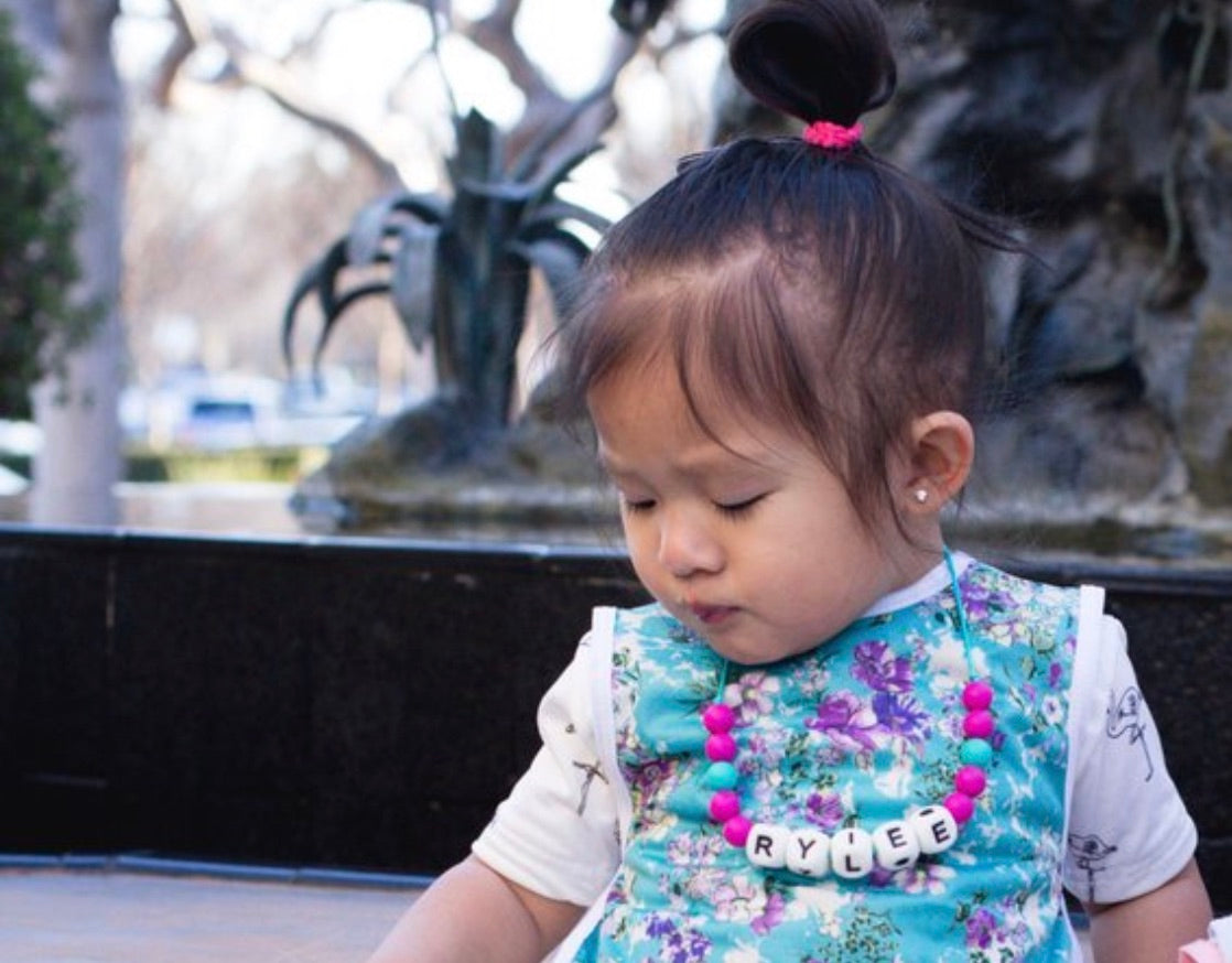 Personalized fidget chew necklace for kids worn by a young girl named Rylee, featuring colorful silicone beads.