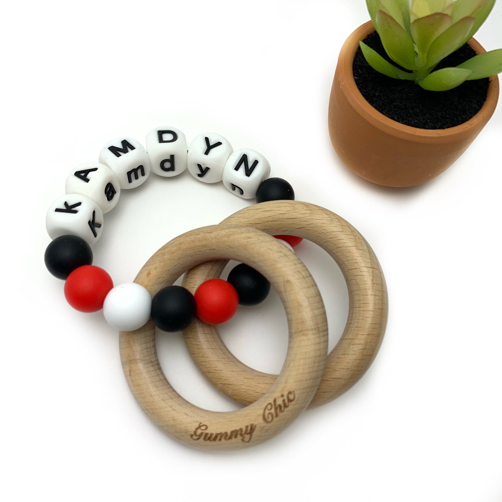 red white and black silicone beads form a teething ring with two wooden rings,