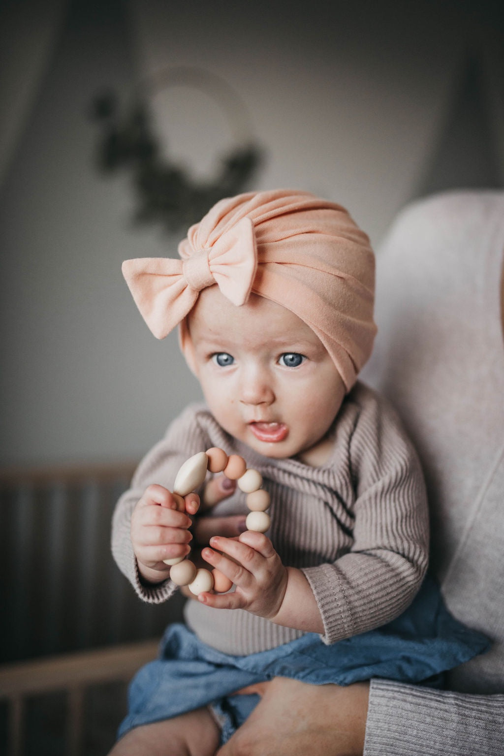 baby in a nursery with mom holding her  holding a teething ring