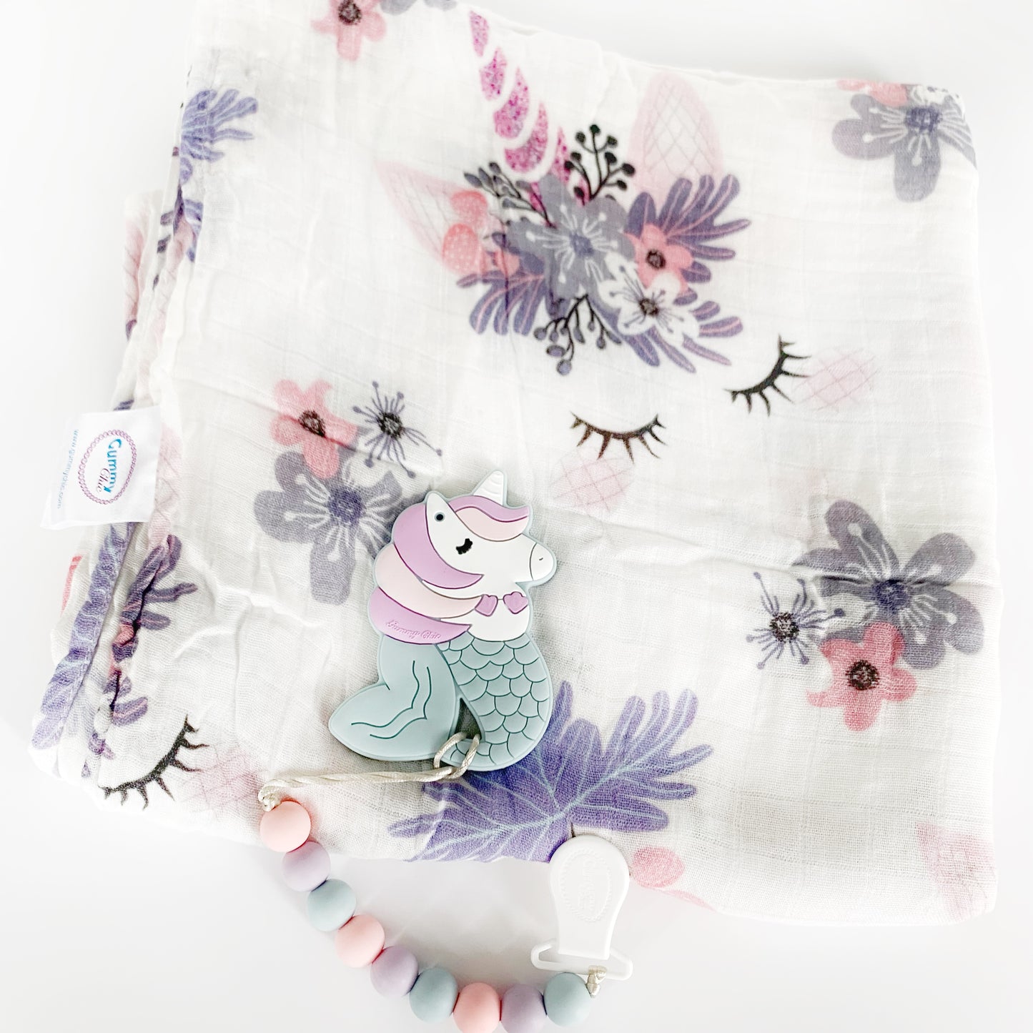 blanket with a white background and the unicorn crown and horns face sleeping, whimsical colors of purple and pink