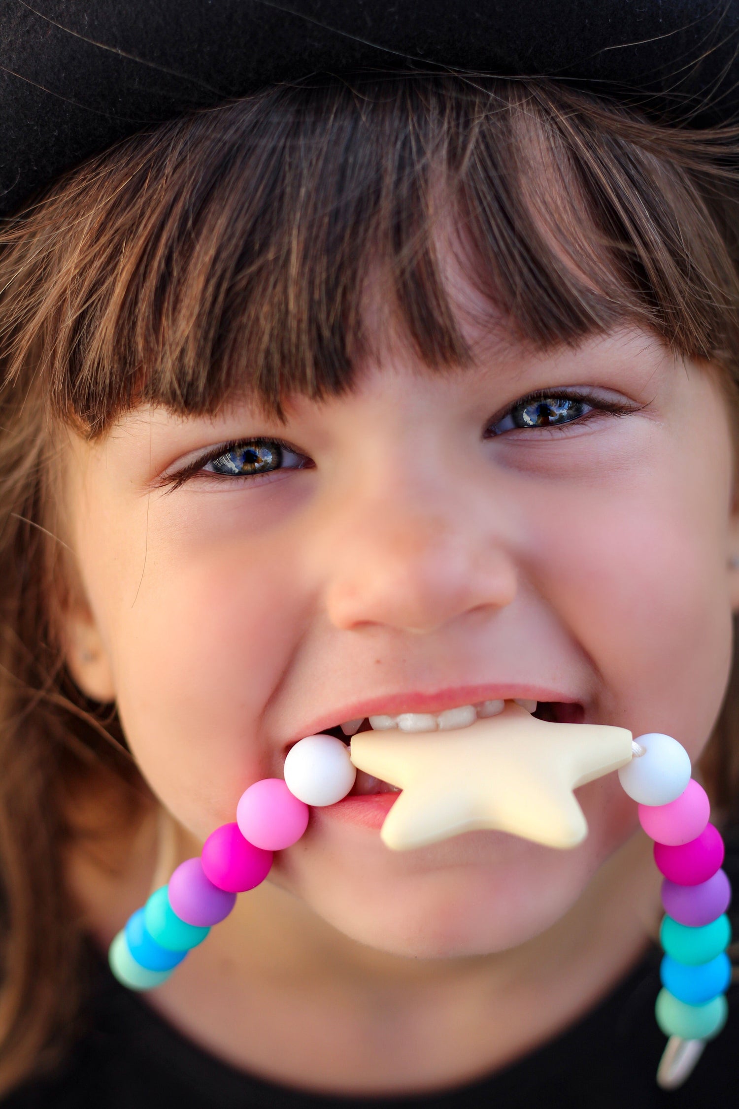 Girl chewing on a silicone star sensory necklace