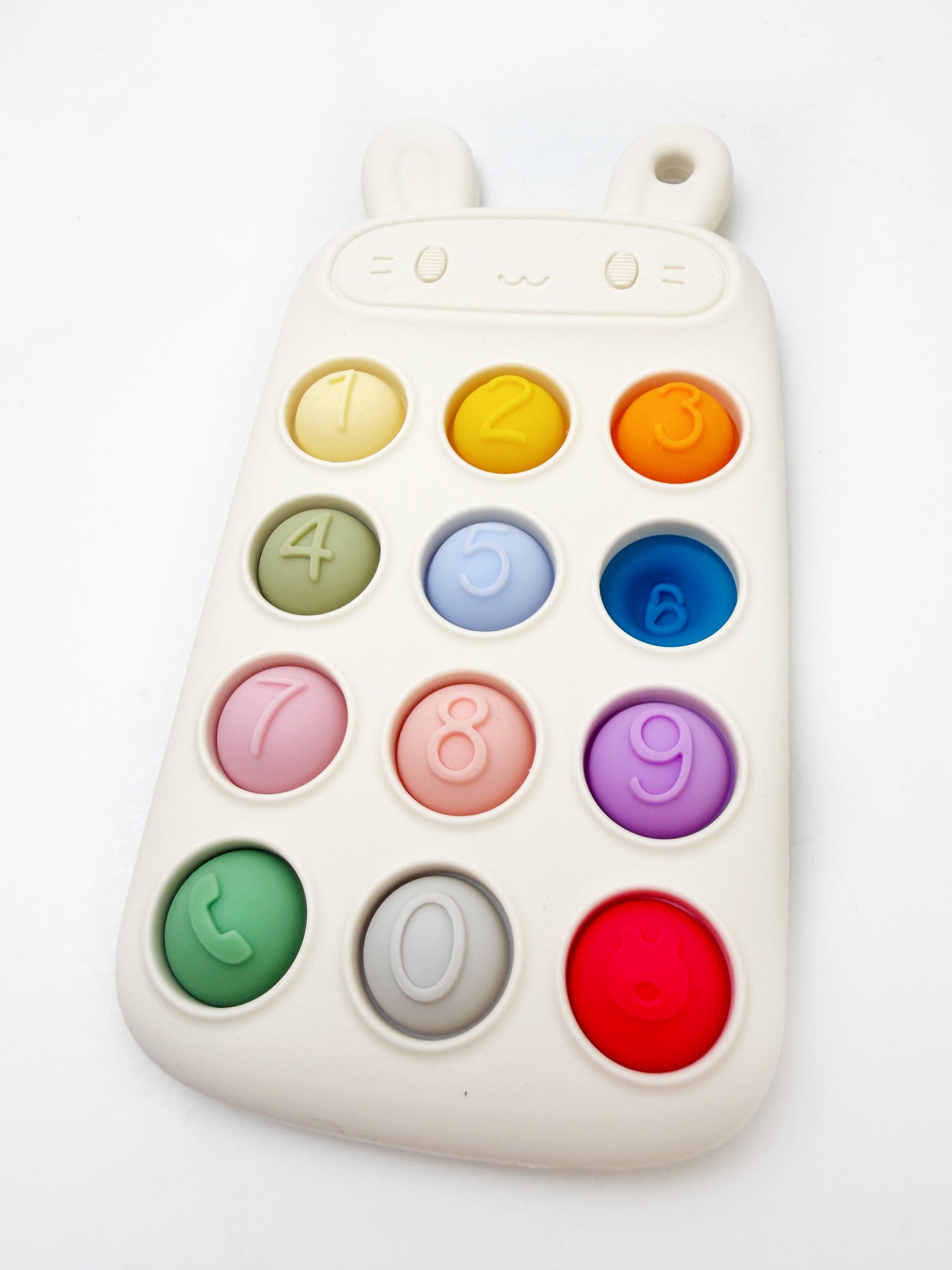 A children's educational toy keypad shaped like a cute animal face with small ears, featuring colorful round buttons numbered 0 through 9 on a white background.