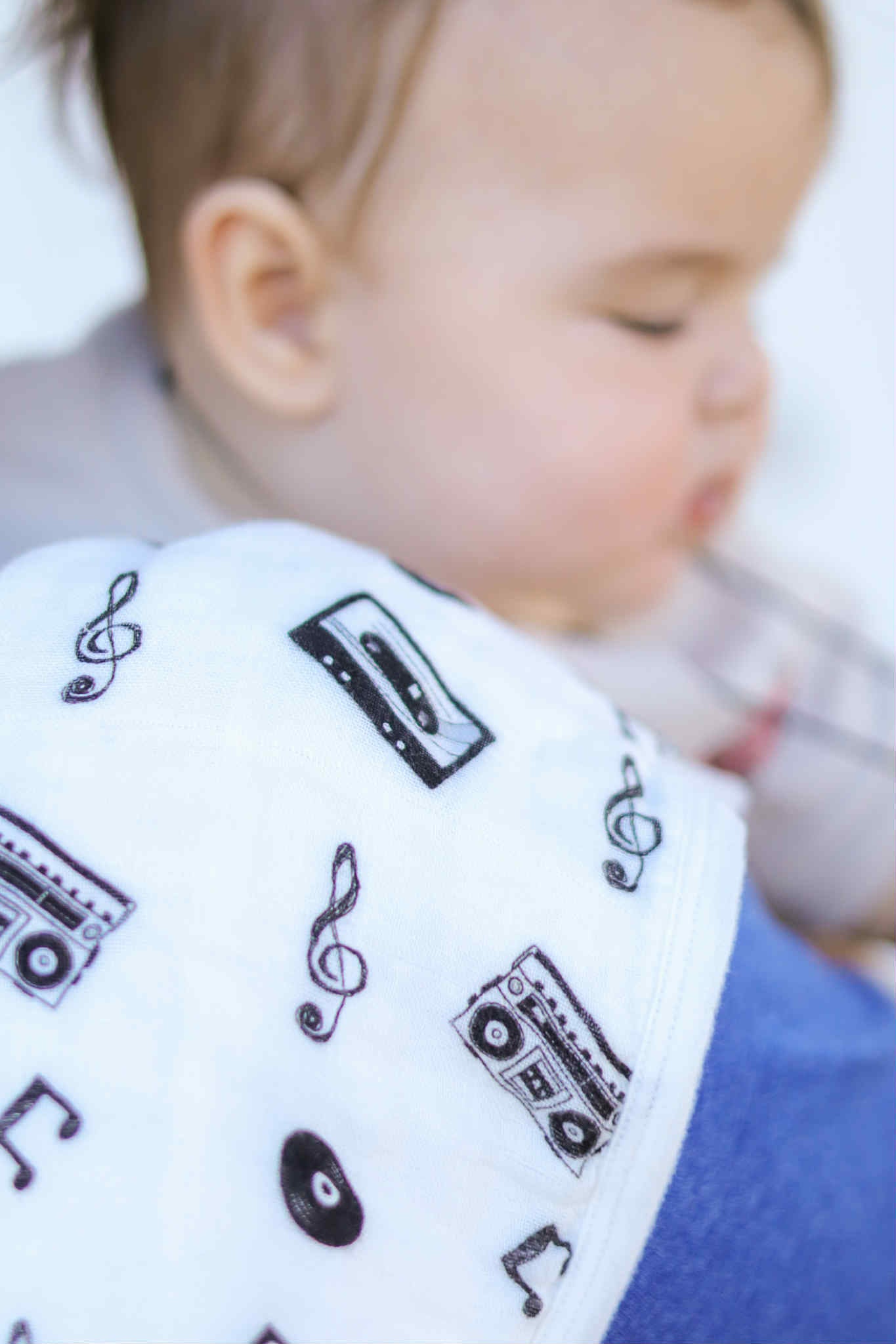 Baby wearing a bib with music-themed patterns on a white background