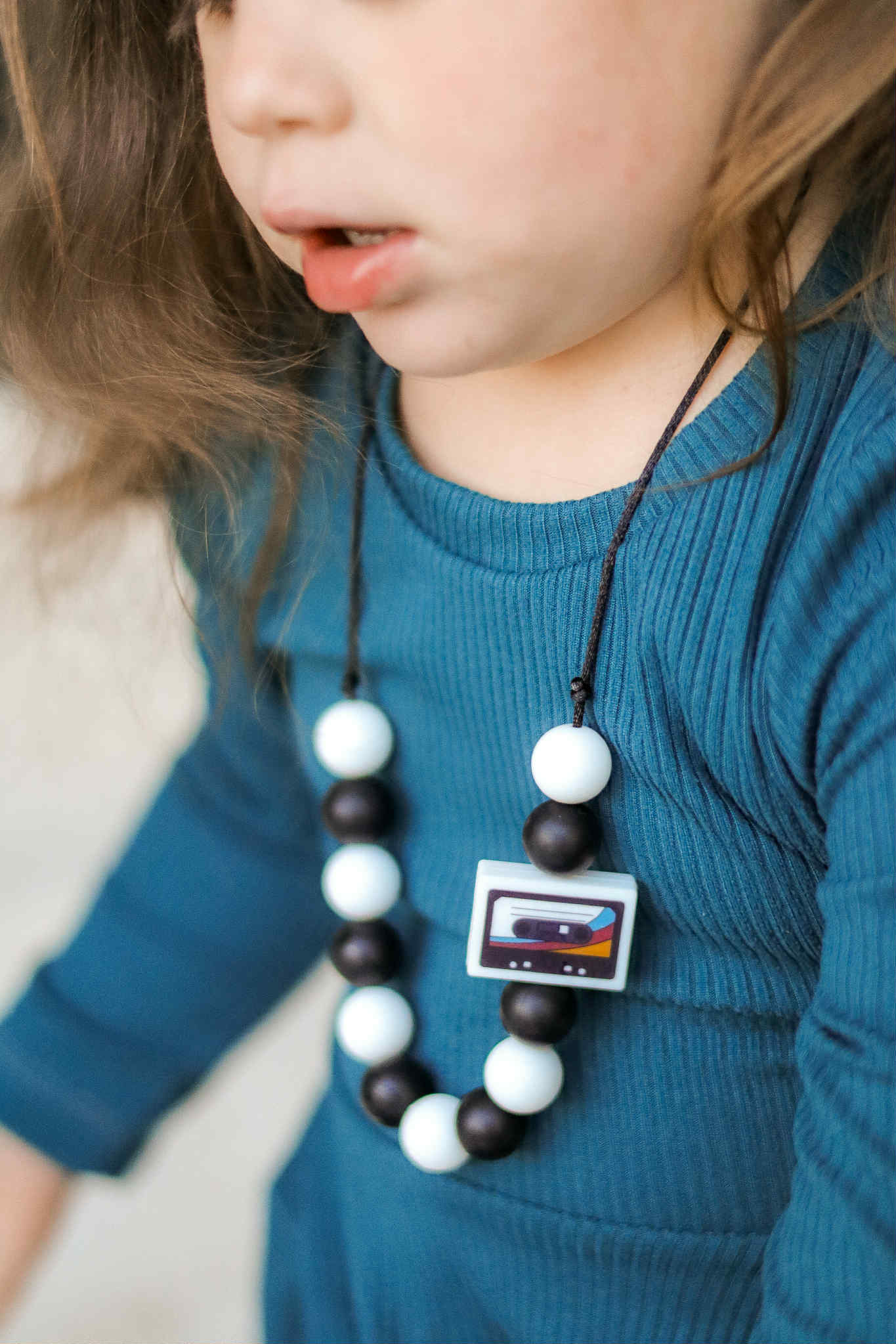 Child wearing a necklace with a colorful pendant