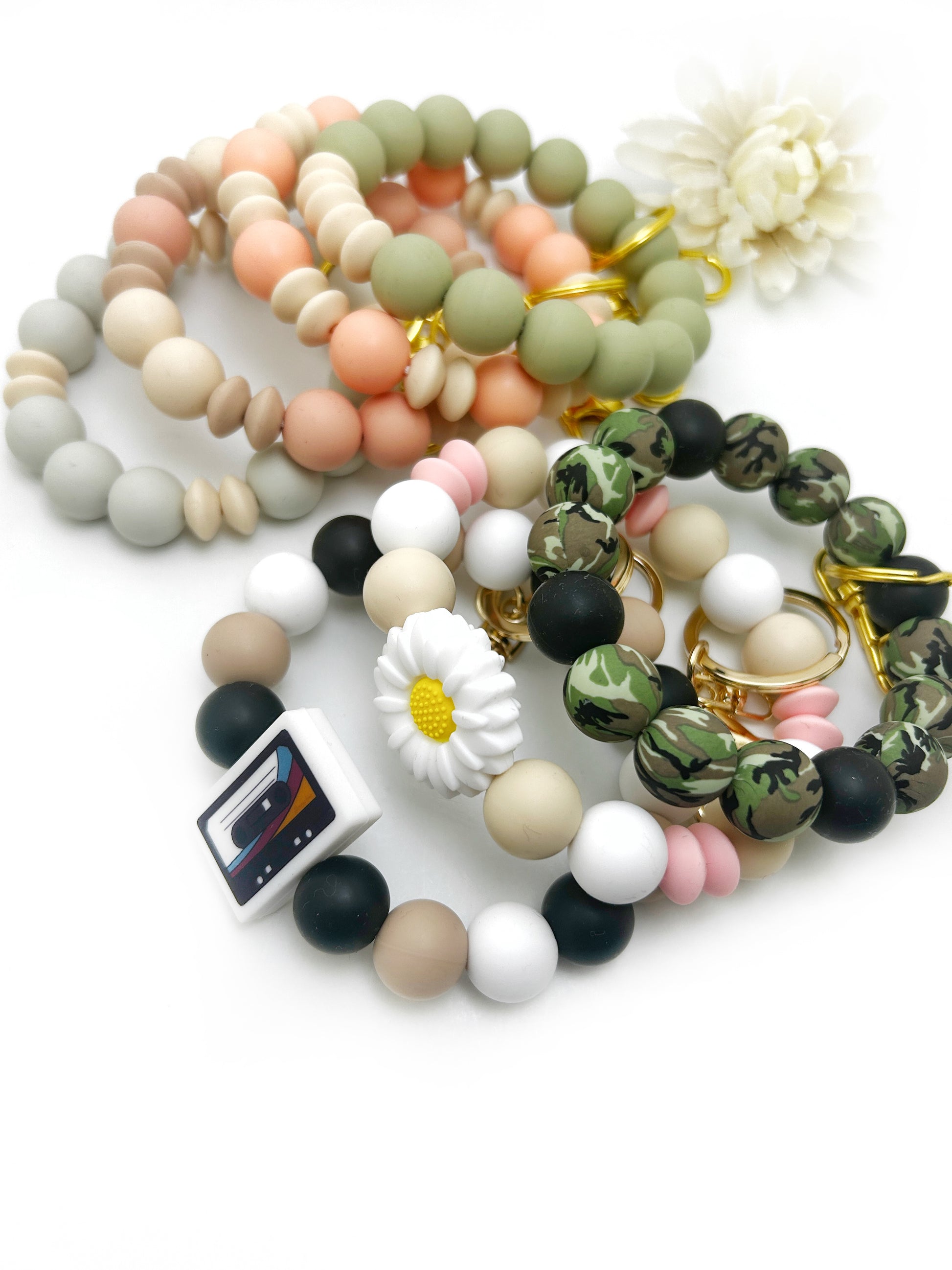 Set of colorful beaded bracelets with floral accents on a white background