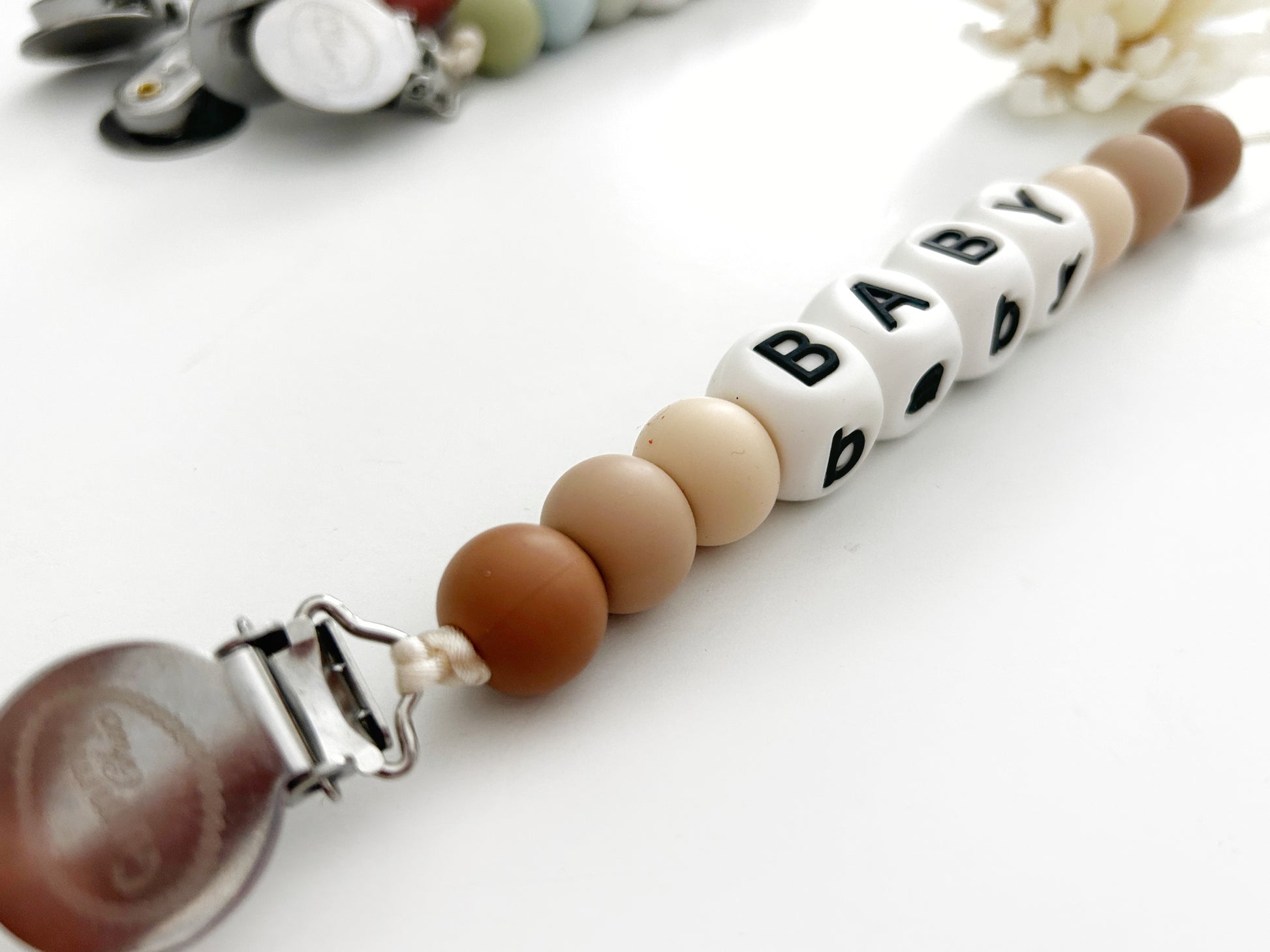 beige, tan and brown silicone beads in a pacifier clip with white and black name beads for a personalized clip