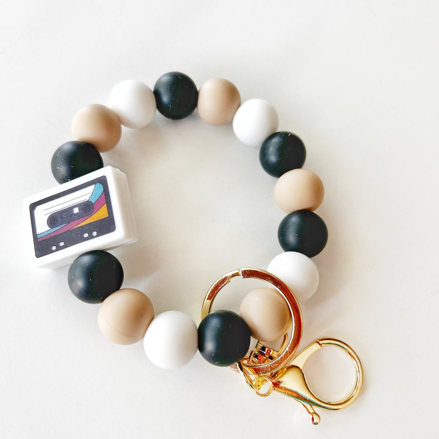 A silicone wristlet keychain with multicolored beads and gold-tone metal clasp and hooks.