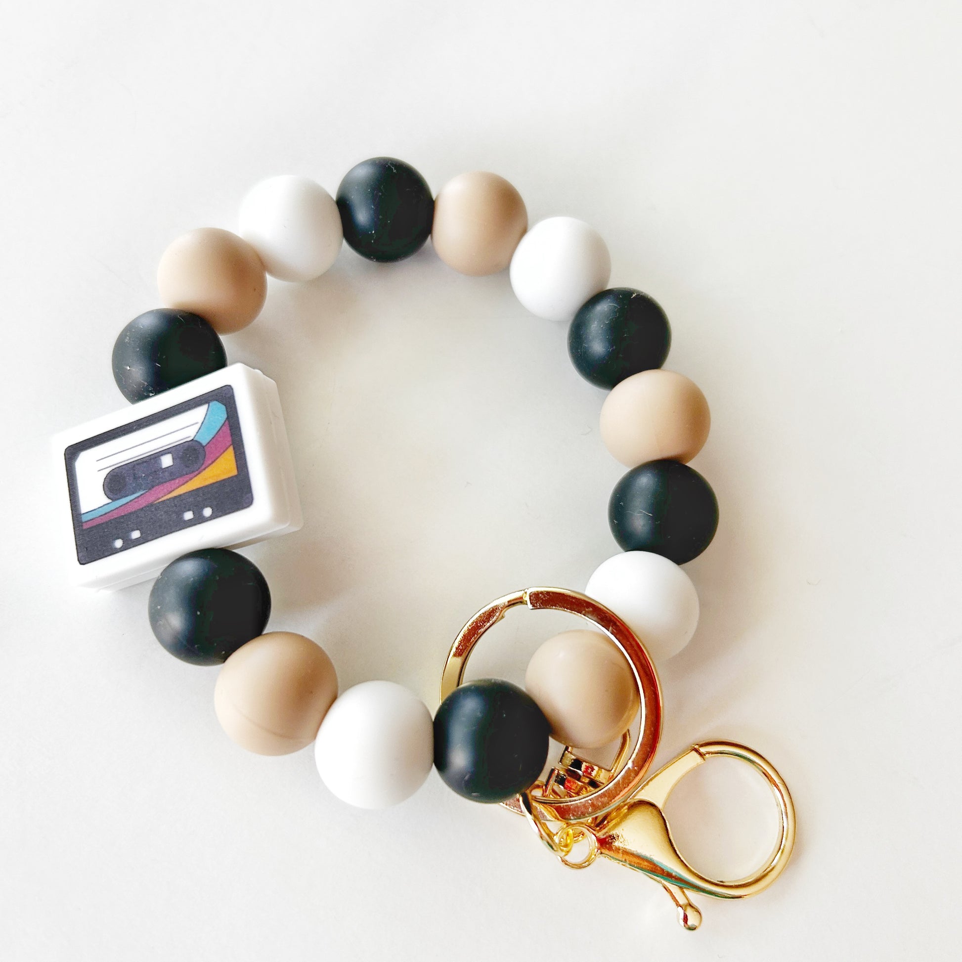 A silicone wristlet keychain with multicolored beads and gold-tone metal clasp and hooks.