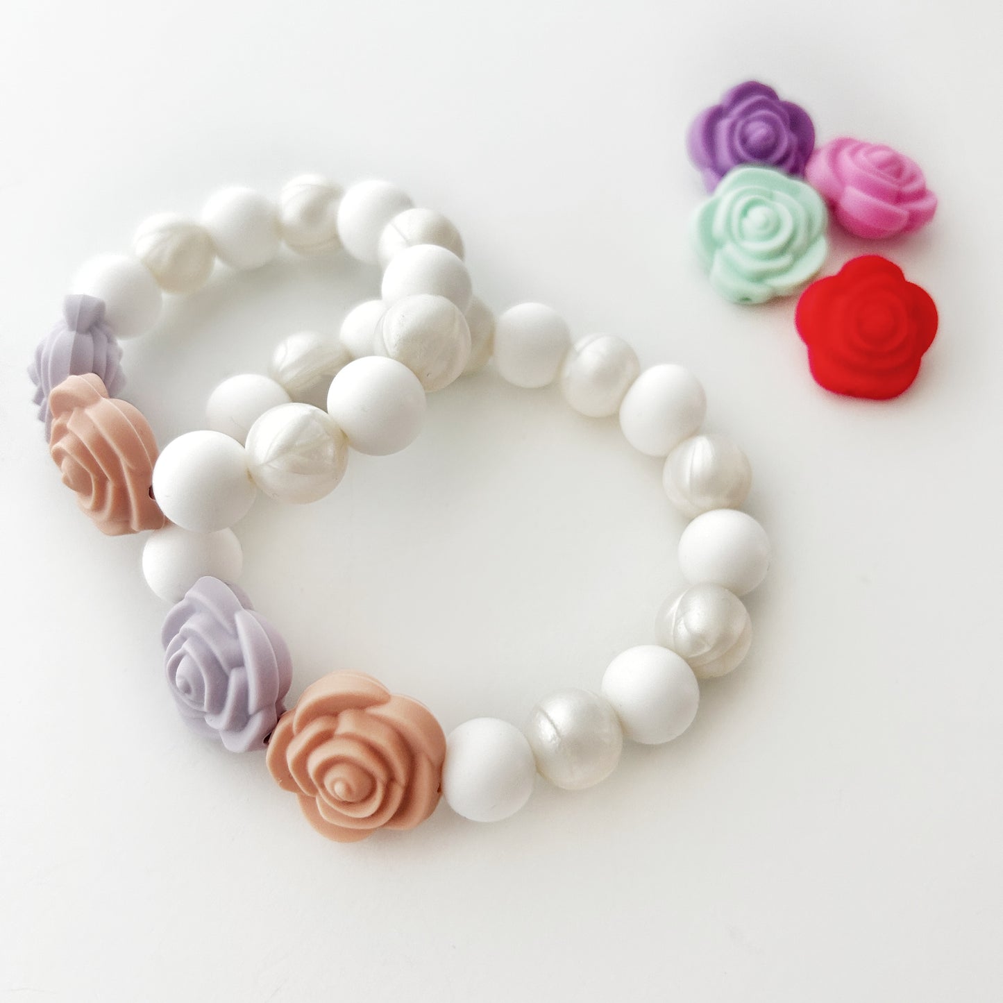 A silicone bracelet with a floral pattern in multiple colors including white, pink, purple, and red, designed for pretend play.