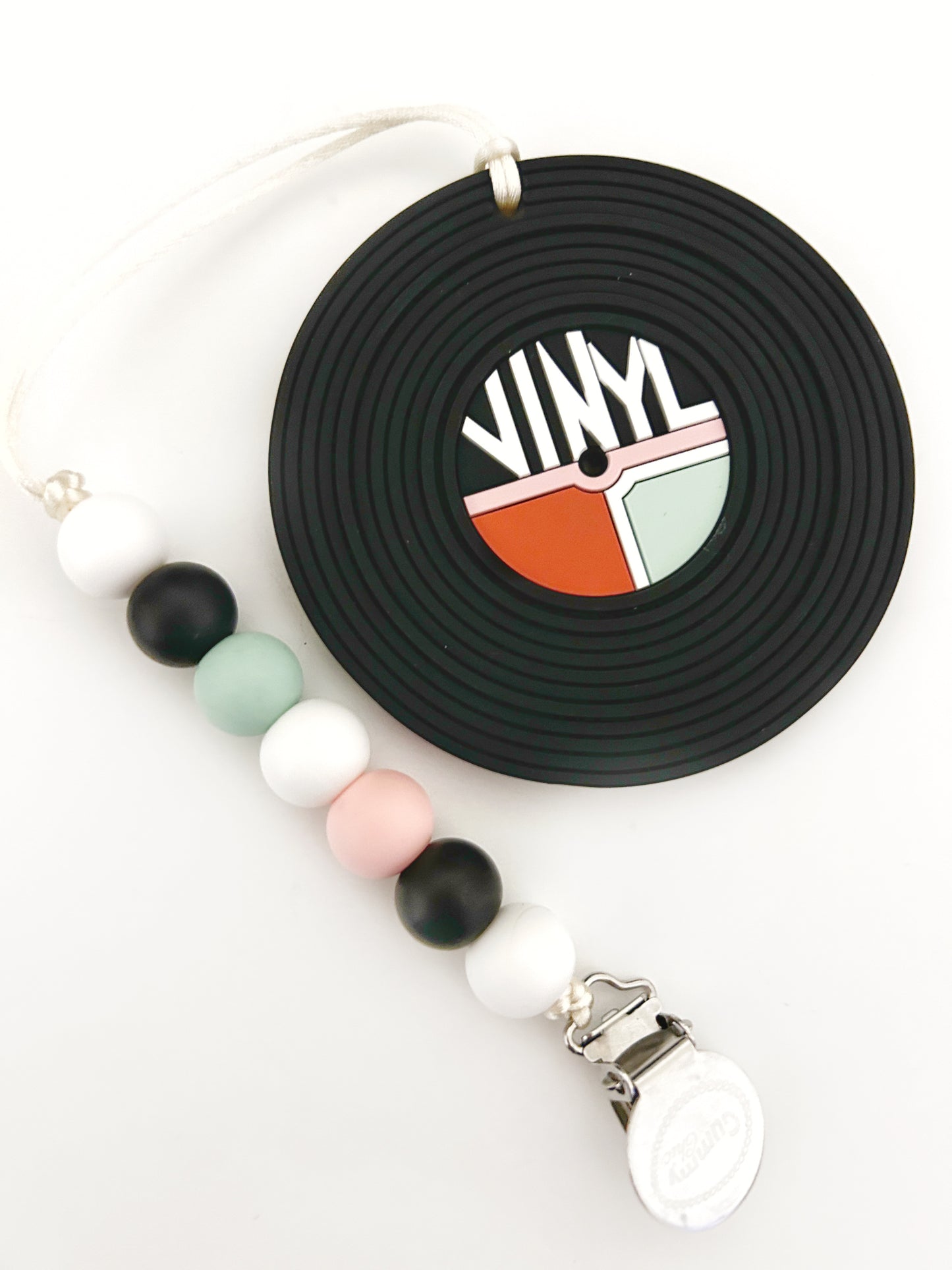 black round teether with vinyl written on it, pink and orange color