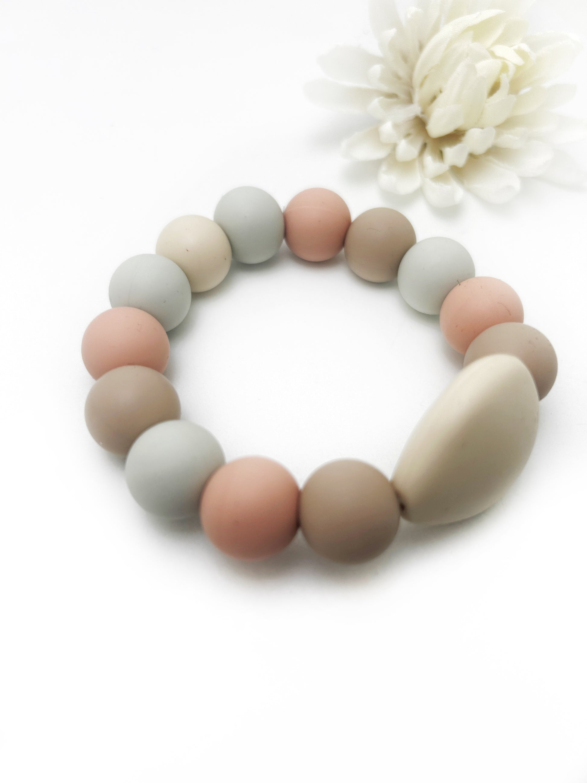 Silicone teething ring with pastel-colored beads on a white background
