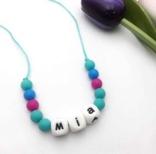 Personalized fidget chew necklace for kids featuring colorful silicone beads and custom name "Mia".