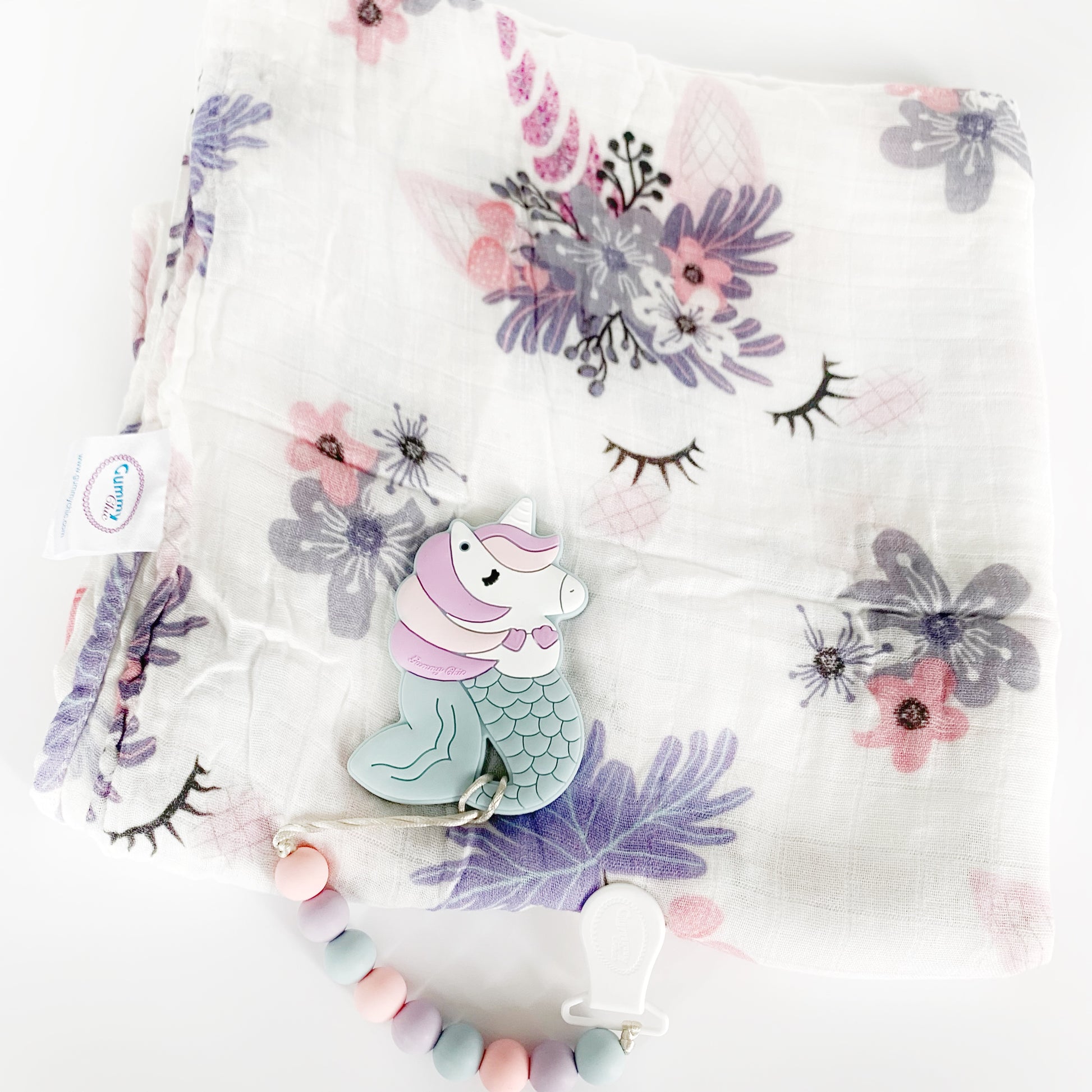 blanket with a white background and the unicorn crown and horns face sleeping, whimsical colors of purple and pink
